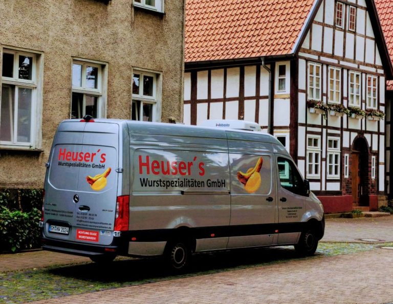 Transporter Silberner Lieferwagen mit Aufschrift "Heuser's Wurstspezialitäten GmbH".